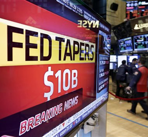 A television screen on the floor of the New York Stock Exchange shows the decision of the Federal Reserve, Wednesday, Jan. 29, 2014.